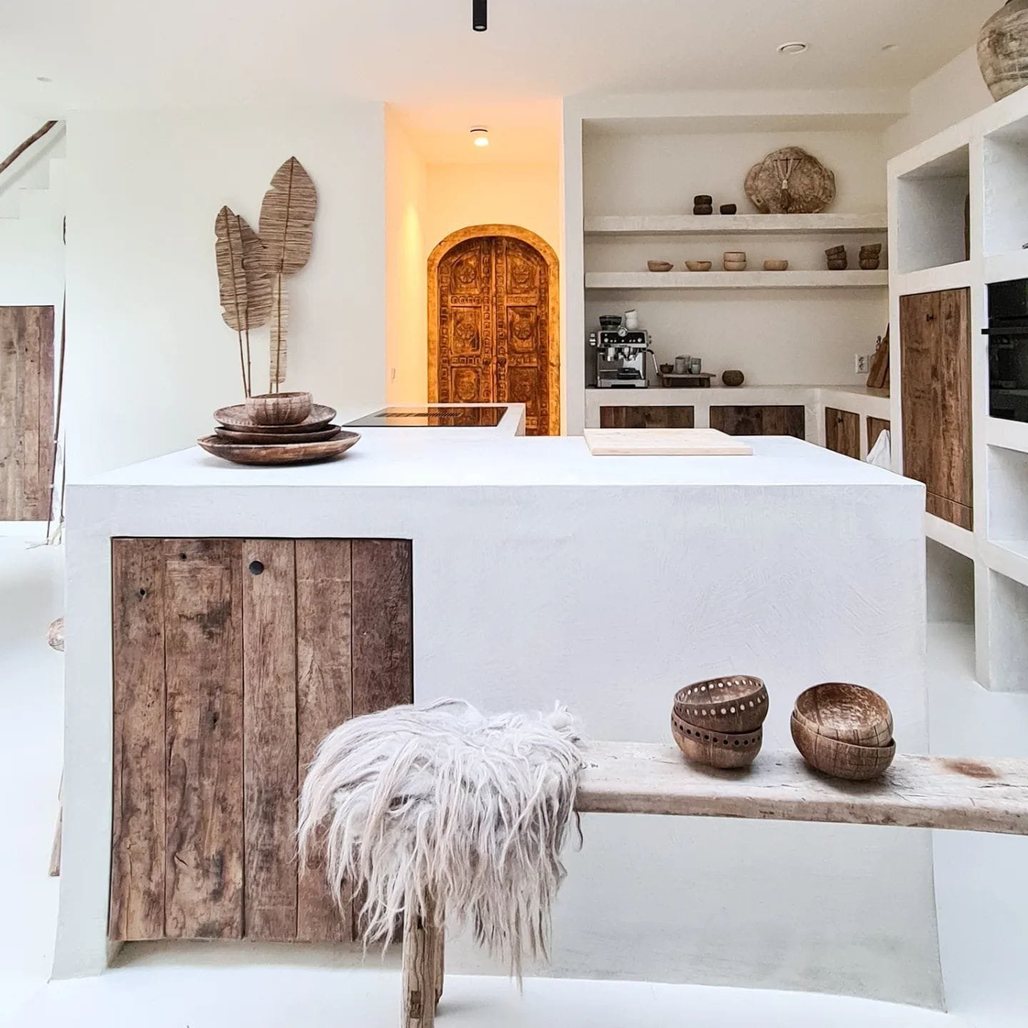 a white kitchen featuring open shelves and a wooden bench in bohemian style captivate the essence of summer home decor paradise throughout the year.
