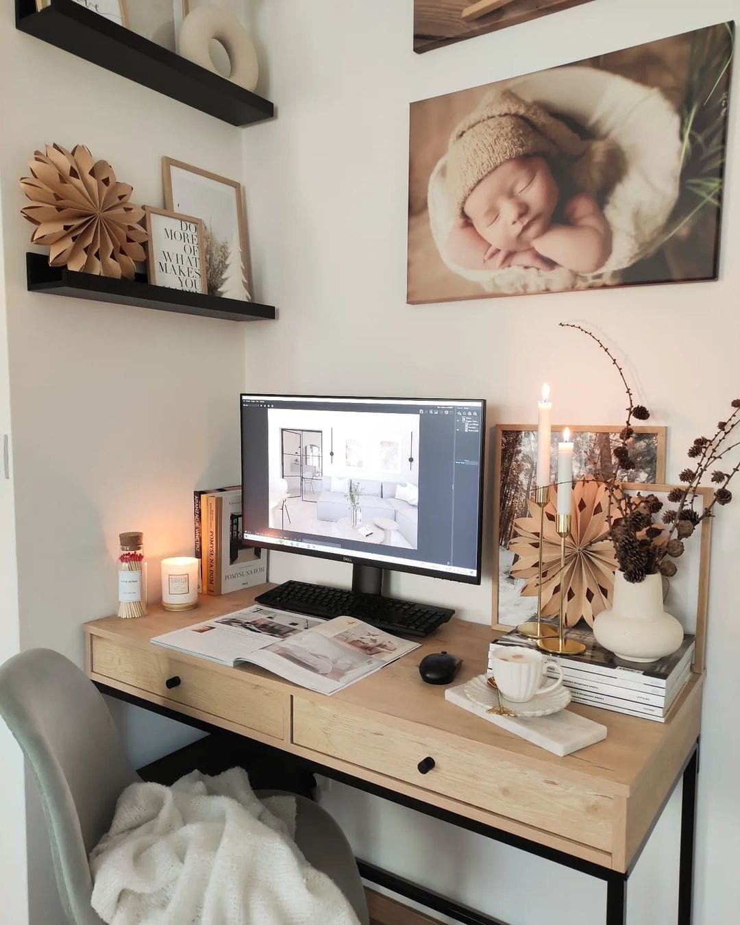 A cozy home office optimized for maximum efficiency, featuring a computer on a wooden desk, decorated with a framed baby photo, candles, and dried flowers.