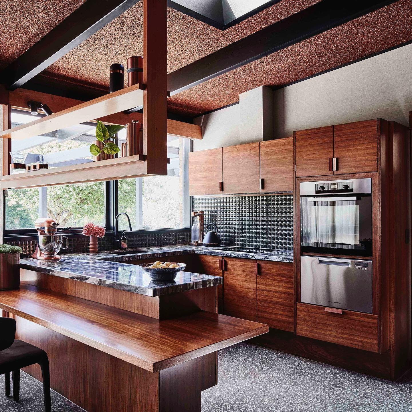 Modern kitchen with wooden cabinets and shelves, a built-in oven, and an island with a black countertop featuring Top 10 Timeless Mid-Century design elements.