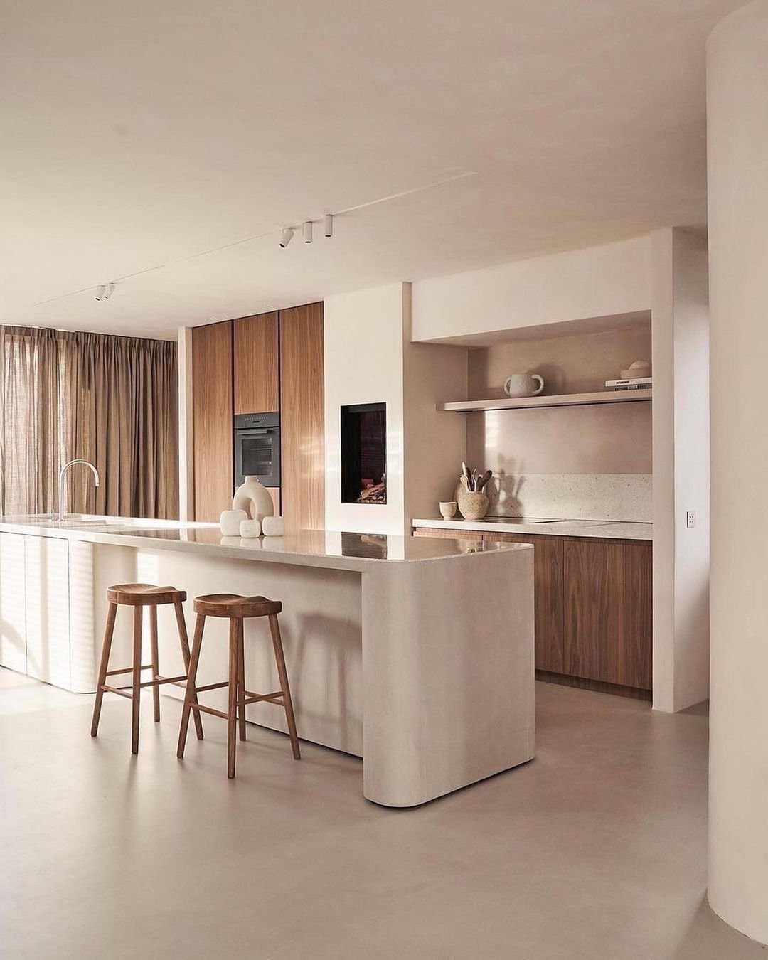 Modern kitchen with minimalist, Japandi-inspired design featuring a marble island counter, two wooden bar stools, wooden cabinets, open shelving, and neutral tones throughout to create a functional and beautiful space.