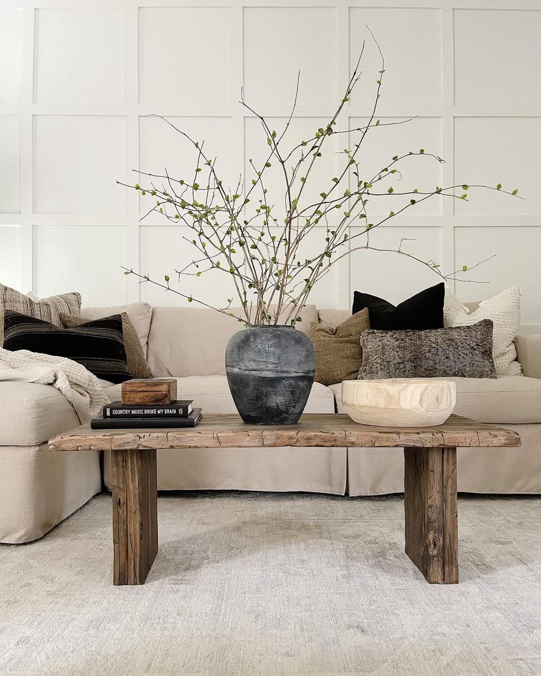 living room coffee table and couch styled with warm throw pillows and a throw blanket