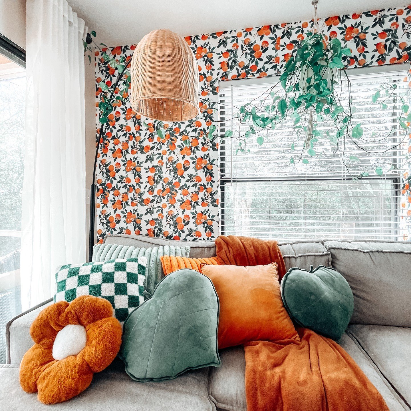 living room sectional styled with colorful and funky shape throw pillows and a colorful wallpaper background make this space vibrant and fun