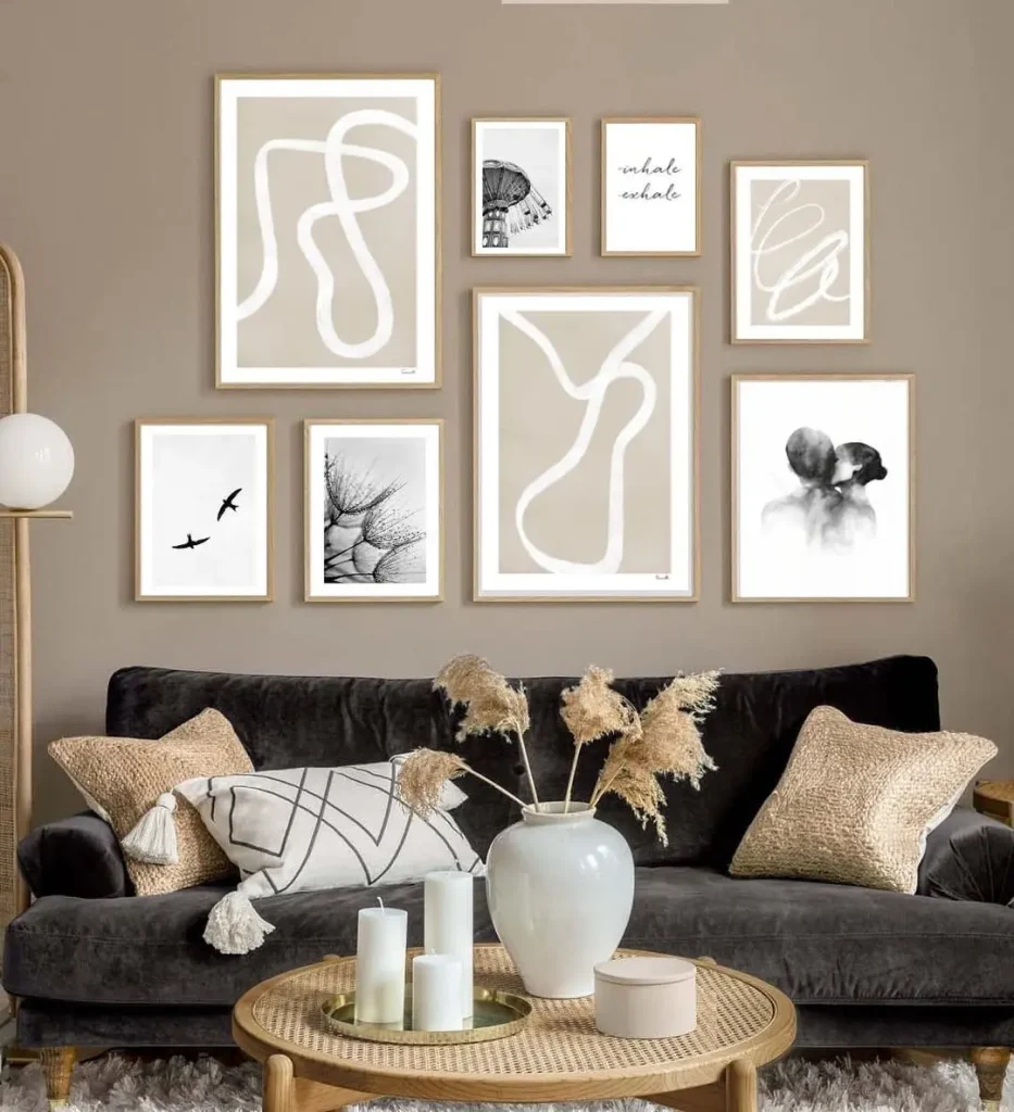 A living room with a dark gray sofa adorned with pillows, a round wooden coffee table with candles and a vase, and a stunning gallery wall featuring abstract and nature-themed framed artworks, showcasing tips on how to create a stunning gallery wall for every room.