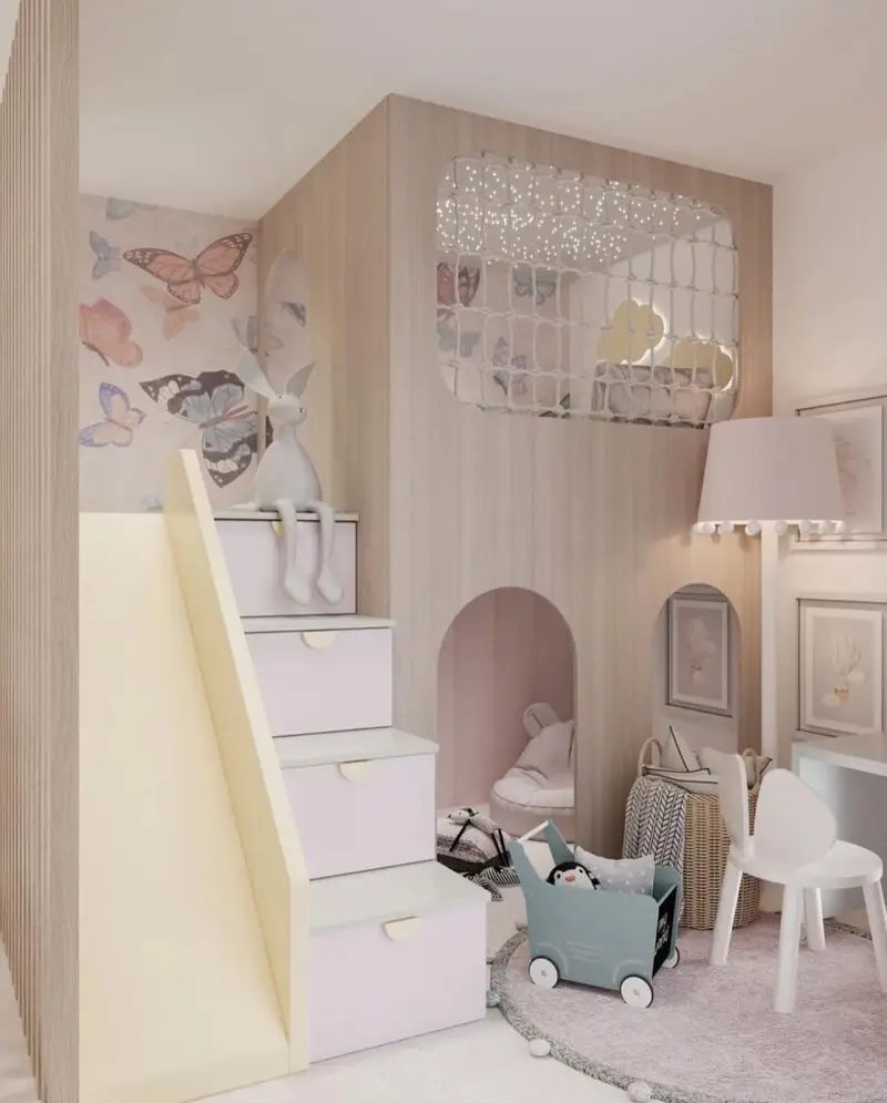 Children’s playroom with a pastel-colored slide, stairs with drawers, butterfly wall art, and a cozy playhouse nook—perfect inspiration for How to Create a Whimsical Pink Bedroom Your Kids Will Love. Toys and framed pictures add playful charm.