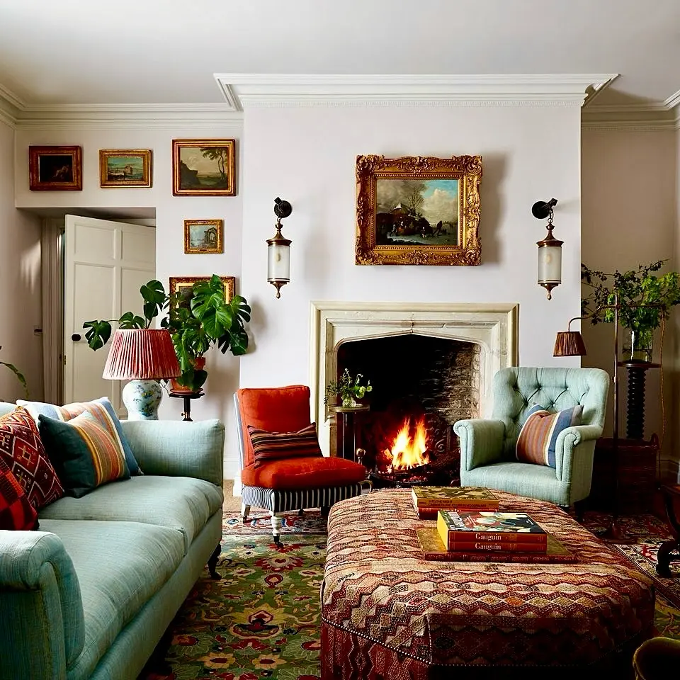 Eclectic vintage living room with colorful furniture, gallery wall artwork, and lit fireplace.